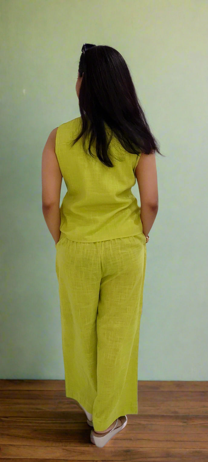 Person wearing a green outfit standing against a white wall.
